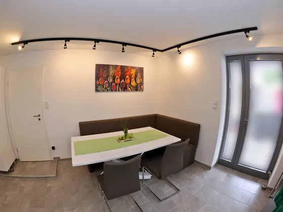 Essbereich mit Eckbank, Esstisch und Blick auf ein Wandbild