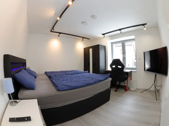 Schlafzimmer mit Boxspringbett, Smart-TV und Bürodrehstuhl